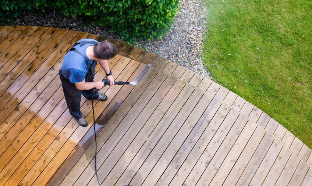 Deck cleaning with a pressure washer on wooden deck