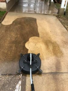 Power washing Pasadena MD concrete walkway with a surface cleaner. Half of the walkway is clean and wet, showing the original concrete color, while the other half is still dirty.