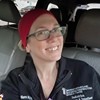 Smiling woman in a black uniform and red headscarf in a car